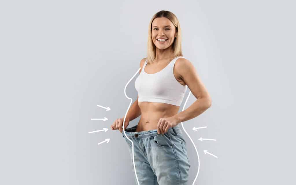 Woman standing in oversized jeans to demonstrate weight loss, with lines indicating her previous size