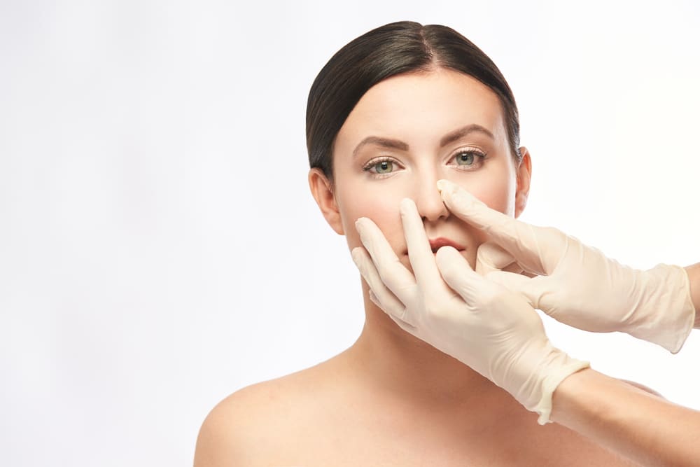 Plastic surgeon examining patient's nose after surgery to correct saddle nose